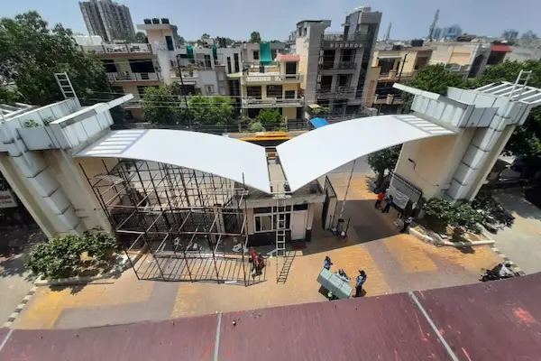 A tensile structure canopy stands prominently in front of a building's entrance door, providing shade and
                                                    shelter.